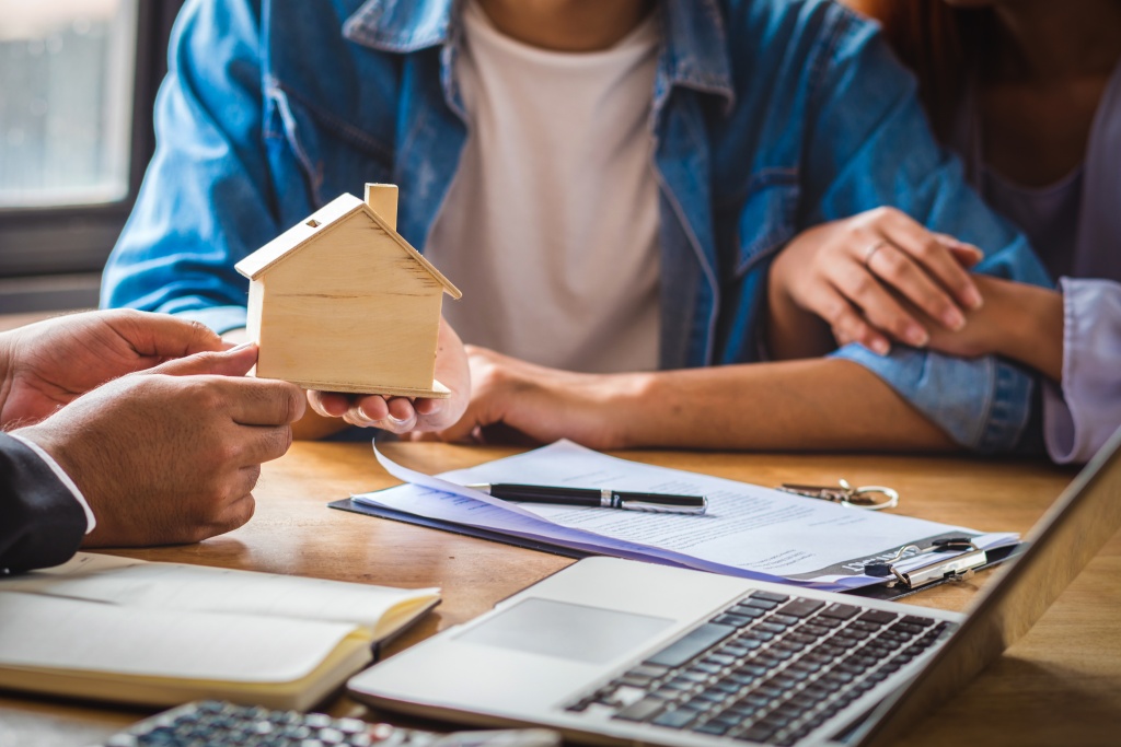 closeup-sale-representative-hand-offer-wooden-house-mockup-asian-young-couple.jpg договор